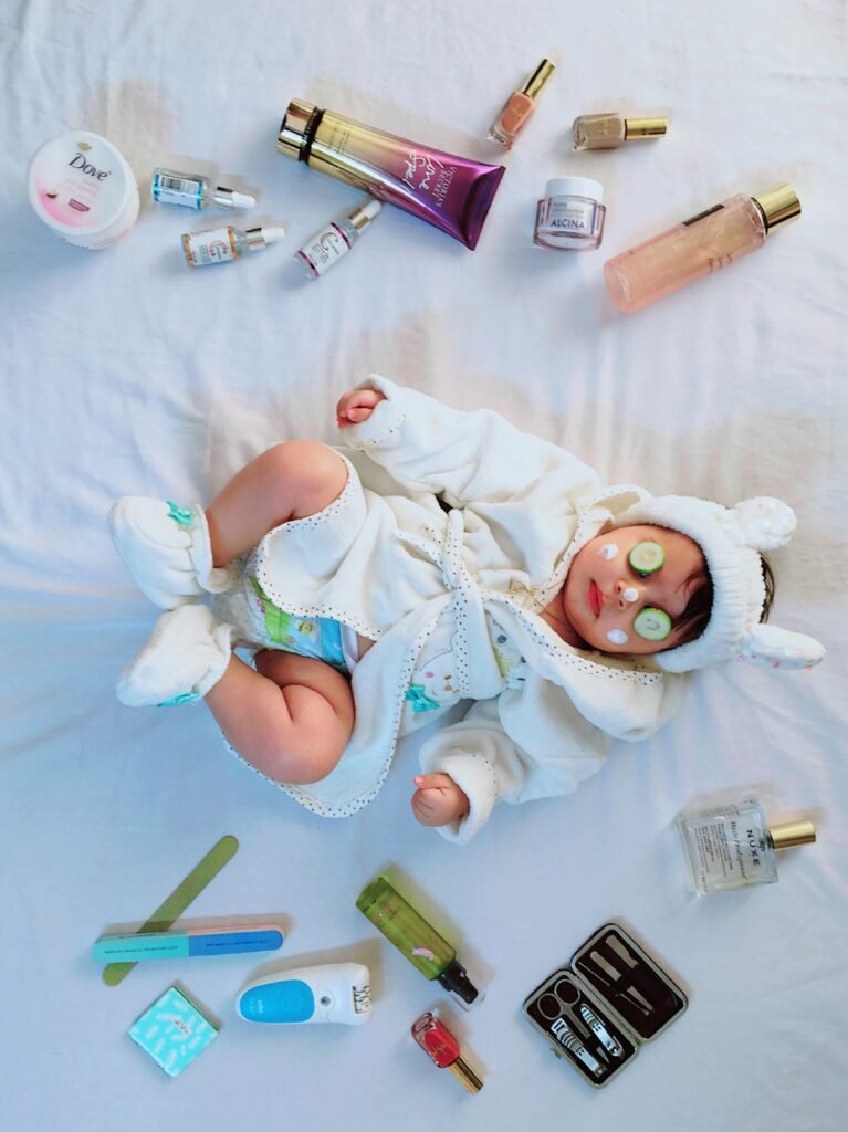 Cute baby with cucumber eye mask surrounded by skincare items on a bed.